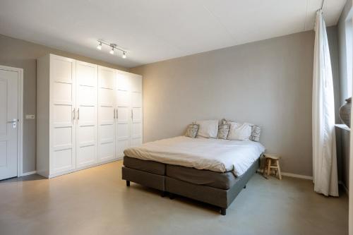 een slaapkamer met een bed en witte kasten bij Appartementen Ossegang in Uithuizen