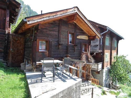 a wooden cabin with a table and chairs in front of it at wooden chalet in Betten near the Aletsch Arena in Betten