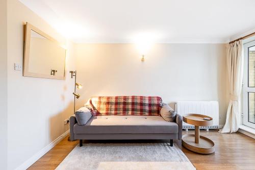 a living room with a couch and a table at Bright Canada Water Waterside Retreat in London