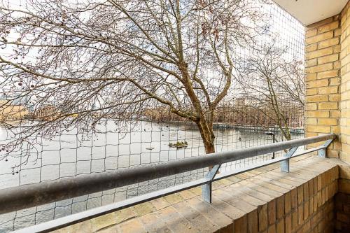 a tree on a wall next to a fence at Bright Canada Water Waterside Retreat in London