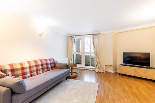 a living room with a couch and a flat screen tv at Bright Canada Water Waterside Retreat in London
