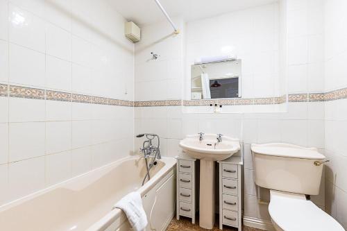 a bathroom with a sink and a toilet and a tub at Bright Canada Water Waterside Retreat in London