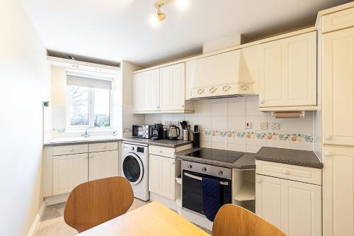 a kitchen with white cabinets and a washer and dryer at Bright Canada Water Waterside Retreat in London