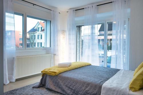 une chambre avec un lit et une grande fenêtre dans l'établissement Modern Station Apartment Mhlin, à Möhlin