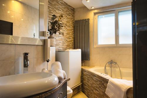 La salle de bains est pourvue d'une baignoire, d'un évier et d'un réfrigérateur. dans l'établissement Modern Station Apartment Mhlin, à Möhlin