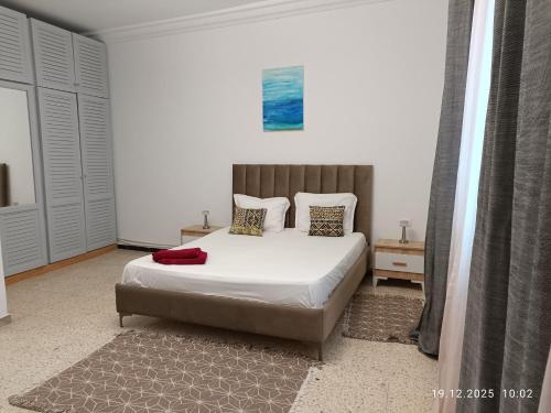 a bedroom with a bed with white sheets and pillows at Résidence Debbabi in Monastir