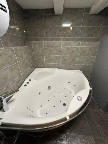 een badkamer met een bad en een tegelwand bij B&M Mini jecuzzi Lovers room Self check-in in Vilnius