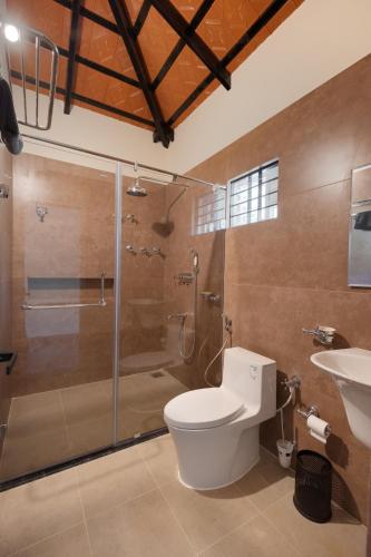 a bathroom with a shower and a toilet and a sink at Samarya Chikkamagaluru in Chikmagalūr