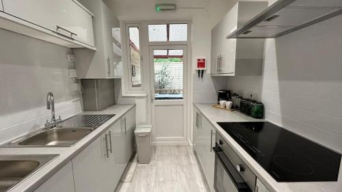 a white kitchen with a sink and a window at Modern Private Ensuite Room,Piccadilly Line,Stylish & Quiet Stay 2 in London