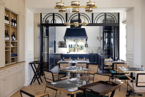 ein Restaurant mit Tischen und Stühlen und einem Kronleuchter in der Unterkunft Maison Douce Époque - Deauville in Bénerville-sur-Mer