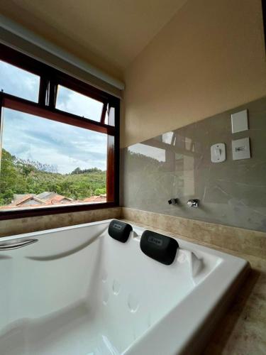 a large white bath tub in a bathroom with a window at Casa Moreira´s Chalés in Monte Verde