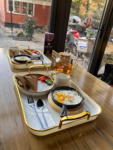 een dienblad met eten op een tafel met eten erop bij Ala-Tor Guest House in Pokrovka