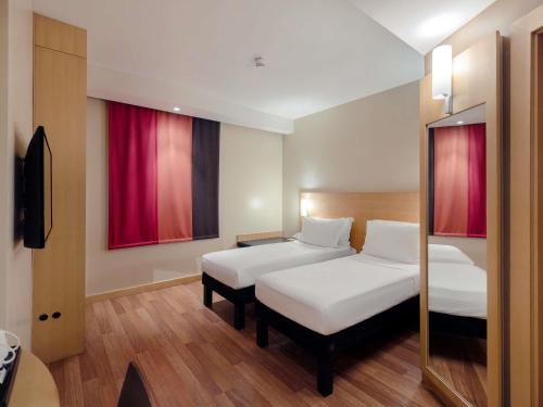 a hotel room with two beds and a mirror at Ibis Riyadh Olaya Street in Riyadh