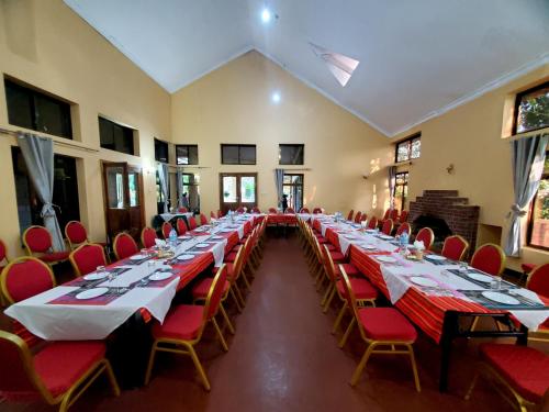 a large room with long tables and red chairs at NGORONGORO CORRIDOR LODGE Karatu in Karatu