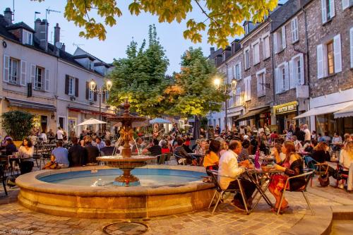 a crowd of people sitting around a fountain in a street at Suite Deluxe - Jacuzzi in Melun
