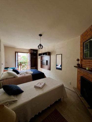 a bedroom with two beds and a fireplace at Casa Moreira´s Chalés in Monte Verde