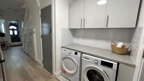 a kitchen with a washer and dryer in a room at Business-Ready Ensuite Room,Desk & Fast WiFi,Piccadilly Line 3 in London
