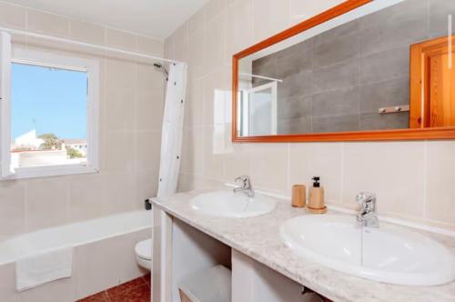 a bathroom with two sinks and a mirror at Villa Jultomas in Cala en Bosc