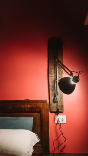 a lamp on a red wall next to a bed at Suite Palazzo Ciolina in LʼAquila