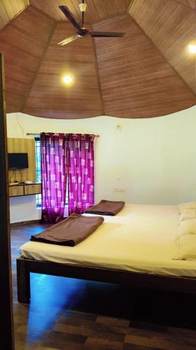 two beds in a room with purple curtains at Adventure Inn Dandeli 2 in Dandeli