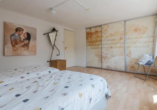 ein Schlafzimmer mit einem Bett und einem großen Gemälde an der Wand in der Unterkunft Vakantiewoning Afterdaan in Elim