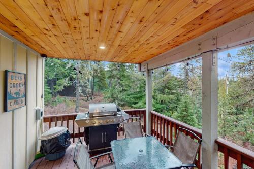 a screened in porch with a grill and chairs on it at Bear Creek Cabin in Government Camp