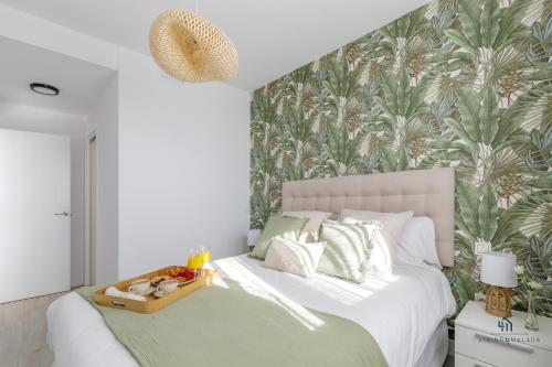 a bedroom with a white bed with a tropical wallpaper at Living4malaga Tower Horizon in Málaga