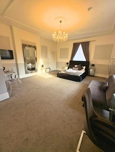 a large living room with a bed and a chandelier at Manor Park Country House in Swansea