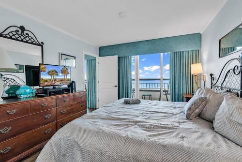a bedroom with a bed and a television and a balcony at Oceanfront Luxury 2BR Litchfield Beach Escape in Pawleys Island