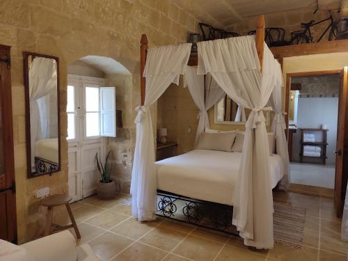 a bedroom with a canopy bed and a mirror at Tal-Barun Farmhouse in San Lawrenz