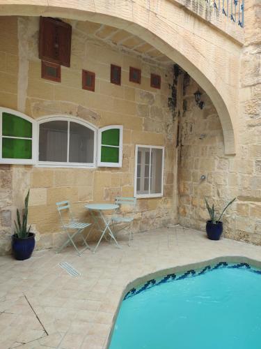 a patio with a table and a swimming pool at Tal-Barun Farmhouse in San Lawrenz