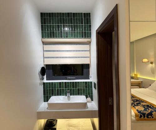 a bathroom with a sink and a green tiled wall at Hoang Long Hotel in Mộ Ðức
