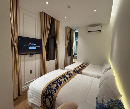 a hotel room with two beds and a flat screen tv at Hoang Long Hotel in Mộ Ðức