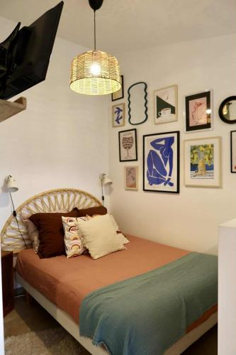 a bedroom with a bed with a television and pictures on the wall at Le joli jardin face à l'Abbaye in Pont-à-Mousson