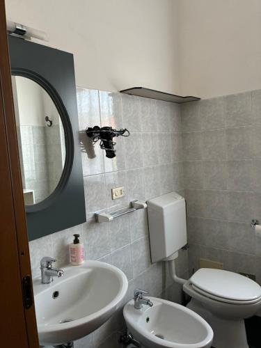 een badkamer met een wastafel, een toilet en een spiegel bij Affittacamere Lively in Novara