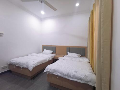 two beds in a small room with white sheets at Sentul KL Private Cozy Bungalow Homestay - Free Parking & Wifi in Kuala Lumpur