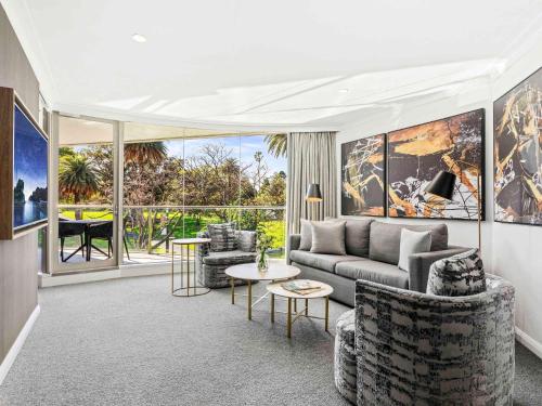 ein Wohnzimmer mit Sofa, Stühlen und einem Tisch in der Unterkunft Pullman Quay Grand Sydney Harbour in Sydney