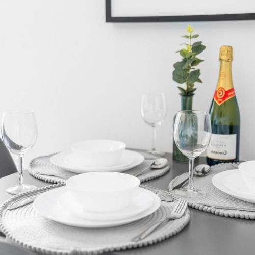 a table with white plates and a bottle of wine at Modern Two Bed Apartment - Sleeps 3 - Parking - Netflix 50C in Netherton