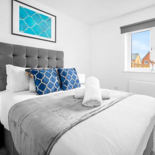 a white bedroom with a large bed with blue pillows at Modern Two Bed Apartment - Sleeps 3 - Parking - Netflix 50C in Netherton