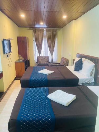 une chambre d'hôtel avec deux lits et une télévision dans l'établissement budget stay-mystique inn, à Ooty