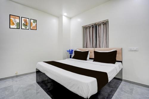 a white bedroom with a large bed with black pillows at HOTEL O THE COZY INN in Sakardarā