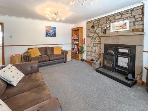 een woonkamer met een bank en een open haard bij Swinton Mill Farm Cottage in Duns