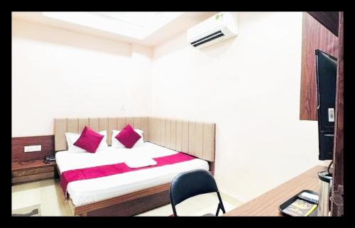 a bedroom with a bed with red pillows and a chair at The Com Fort Inn 