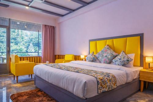 a bedroom with a large bed with a yellow headboard at Apple Flower Mountain View Hotel in Manāli