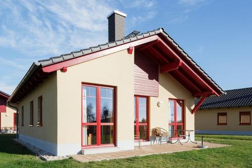 a small house with red windows and a patio at Holiday home in Markkleeberg near a lake in Markkleeberg