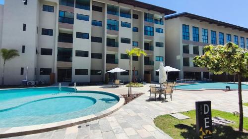 een hotel met een zwembad en een gebouw bij Max Carneiros Suítes - Com e sem piscina privativa in Praia dos Carneiros