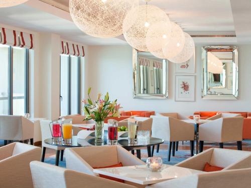 a restaurant with tables and chairs and a chandelier at JA Ocean View Hotel, Jumeirah Beach Dubai in Dubai