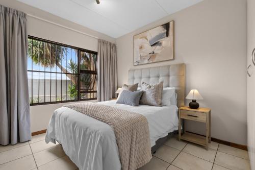 a white bedroom with a bed and a window at Prime location in upmarket security estate in Johannesburg