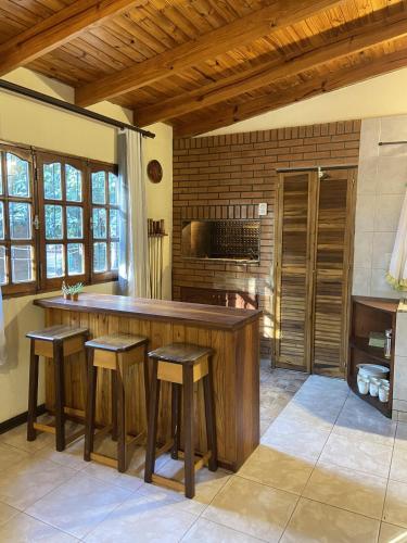 a kitchen with a large wooden counter with stools at Cabaña Conectar Naturaleza in Ituzaingó