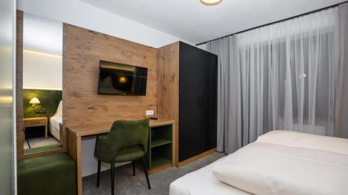 a bedroom with a bed and a desk with a television at das MOOSWALD in Obsteig